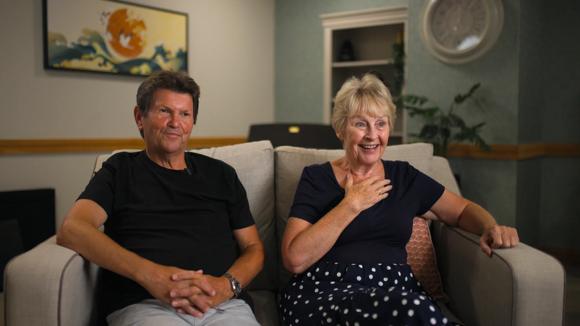 A family member and a resident sitting together in a care home lounge.
