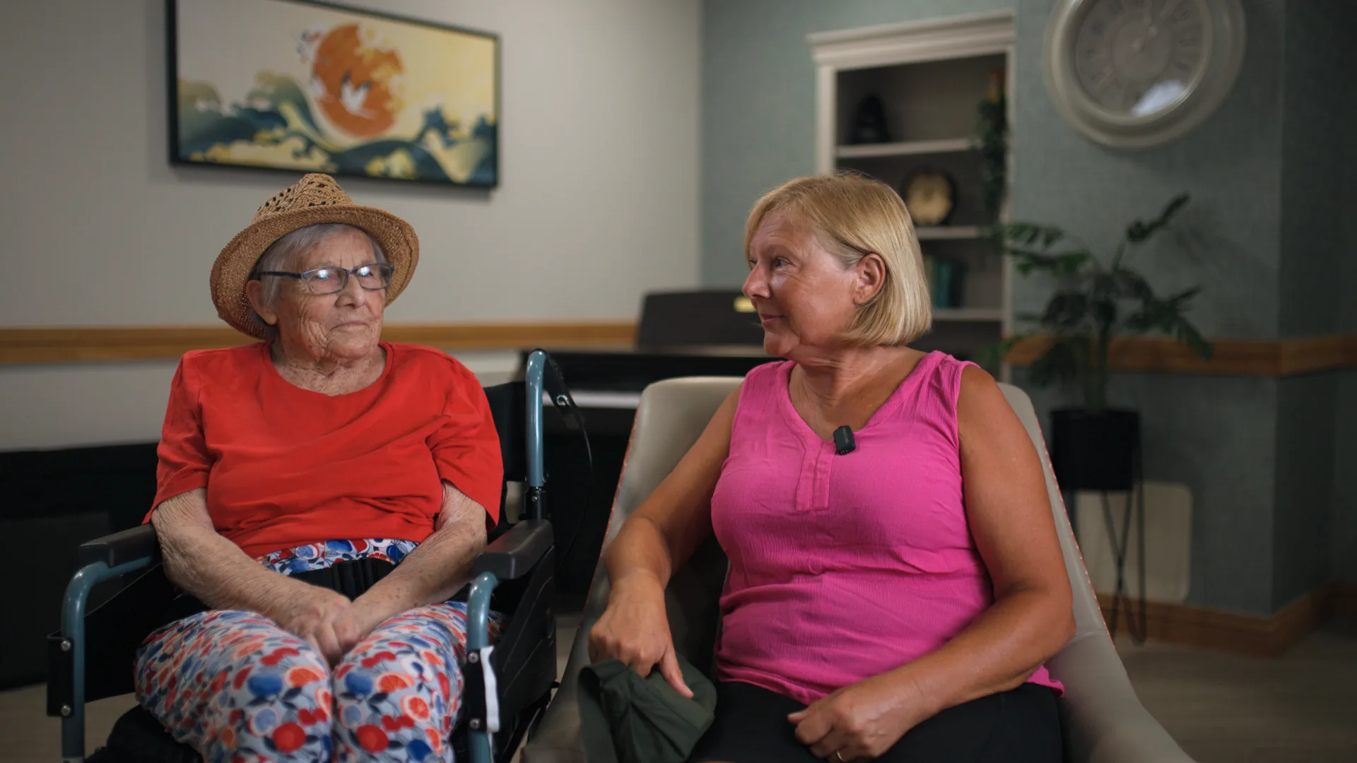 A resident in conversation with her daughter in a care home lounge.