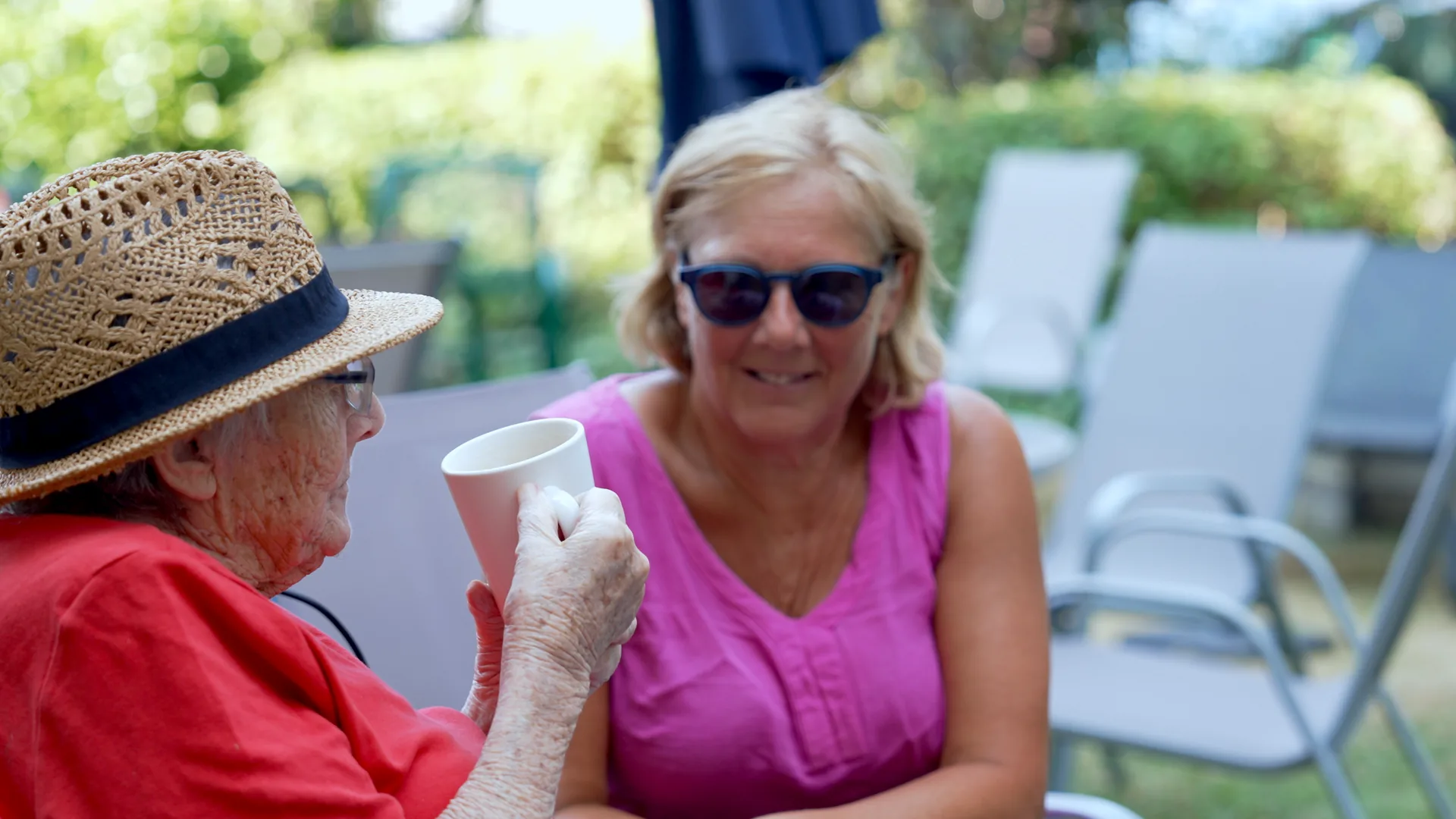 A resident and a visitor having tea together in the garden.